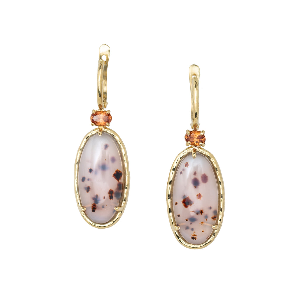 Pair of gold earrings with speckled stone pendants on a white background
